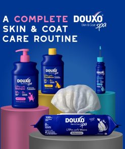 DOUXO Spa skin and coat care routine set featuring a DOUXO Itch Soothing Shampoo, DOUXO Oatmeal Conditioner, DOUXO Dewaxing ear cleaner, and DOUXO multipurpose wipes arranged on colorful pedestals against a blue background.